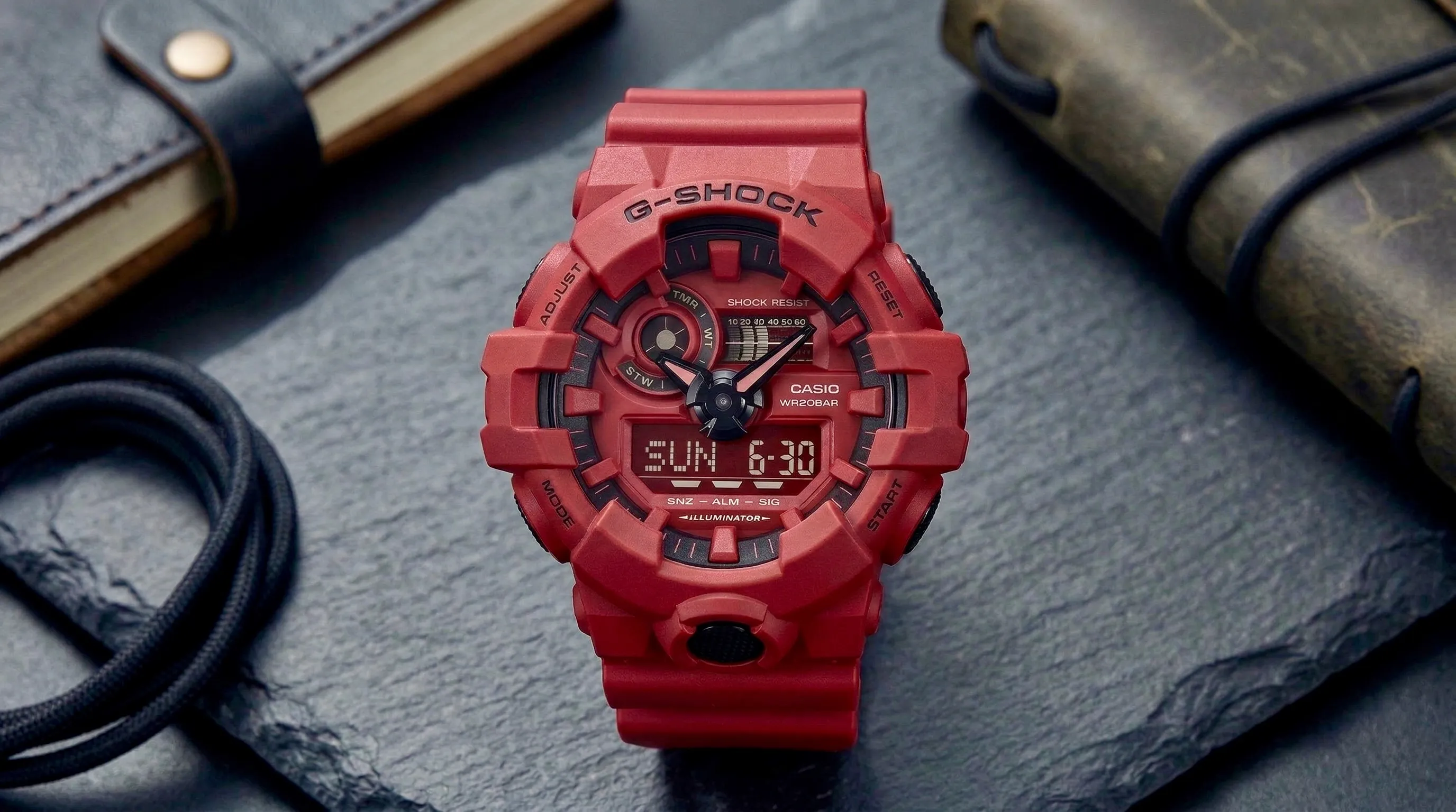 Close-up of a red G-SHOCK wristwatch with digital and analog displays on a dark slate surface